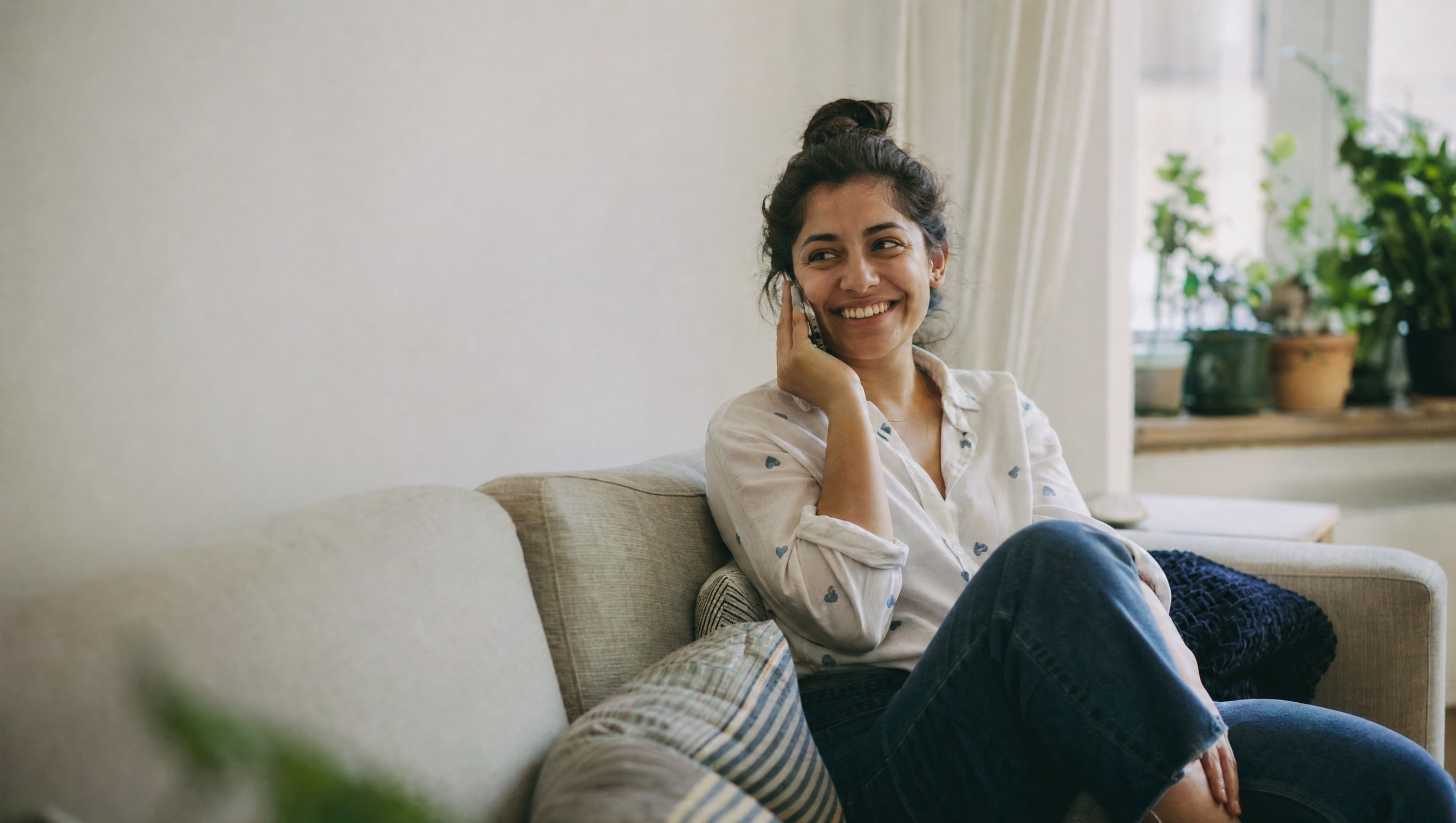 A relaxed customer smiling on a phone call at home